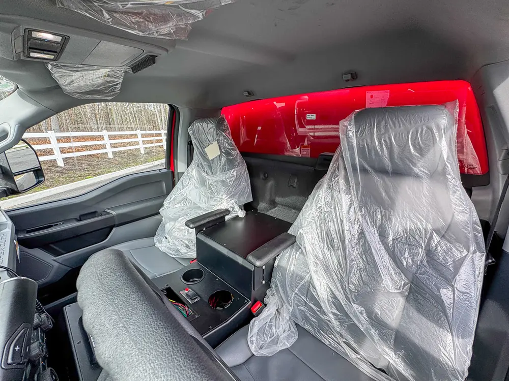 Exterior view of small fire truck showing cab, body compartments, and wheel/tire area.