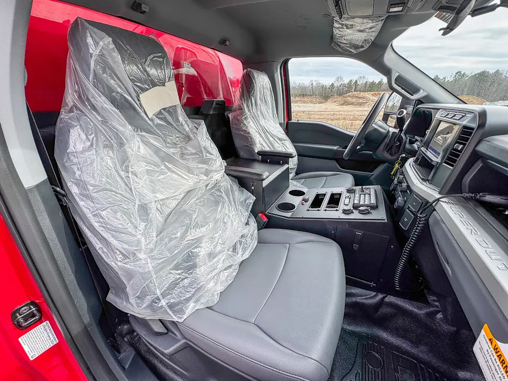 Exterior view of small fire truck showing cab, body compartments, and wheel/tire area.