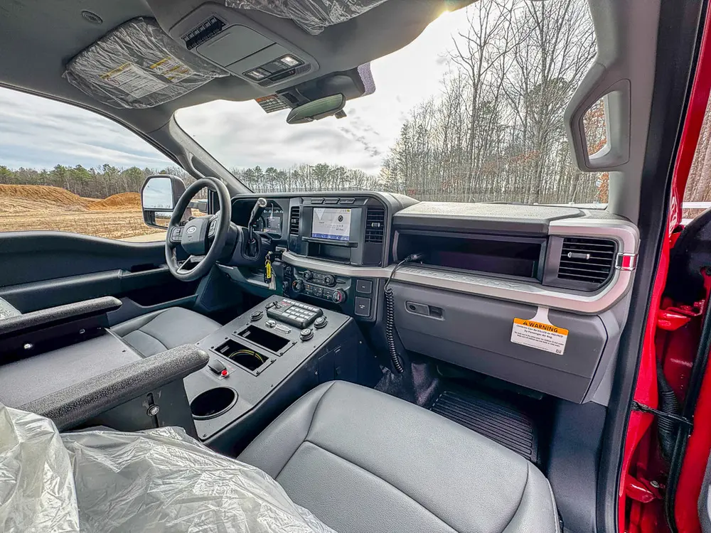 Exterior view of small fire truck showing cab, body compartments, and wheel/tire area.