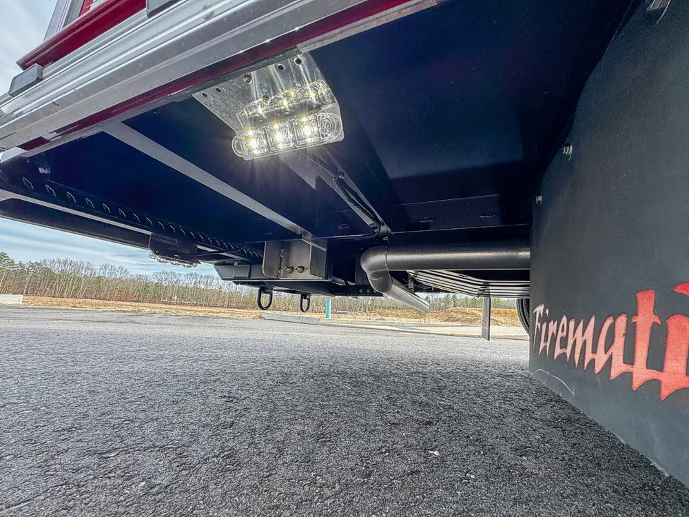 Exterior view of small fire truck showing cab, body compartments, and wheel/tire area.