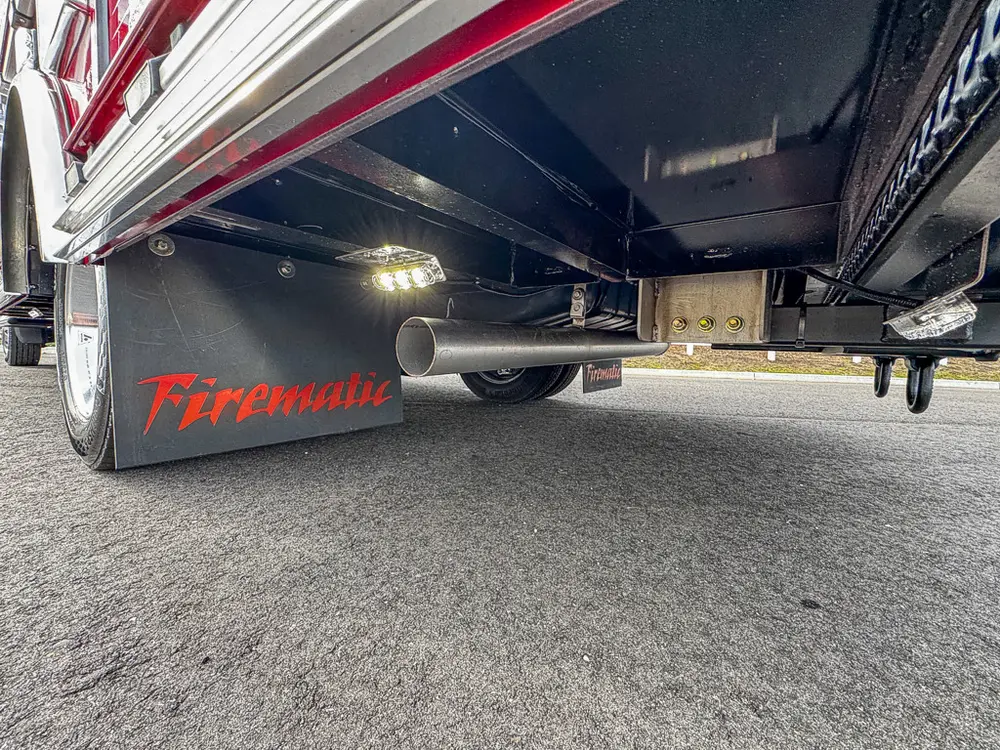 Exterior view of small fire truck showing cab, body compartments, and wheel/tire area.