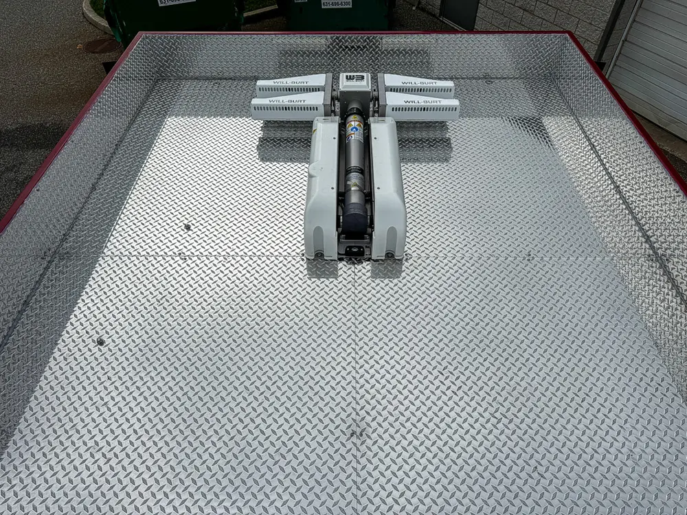 Exterior view of small fire truck showing cab, body compartments, and wheel/tire area.