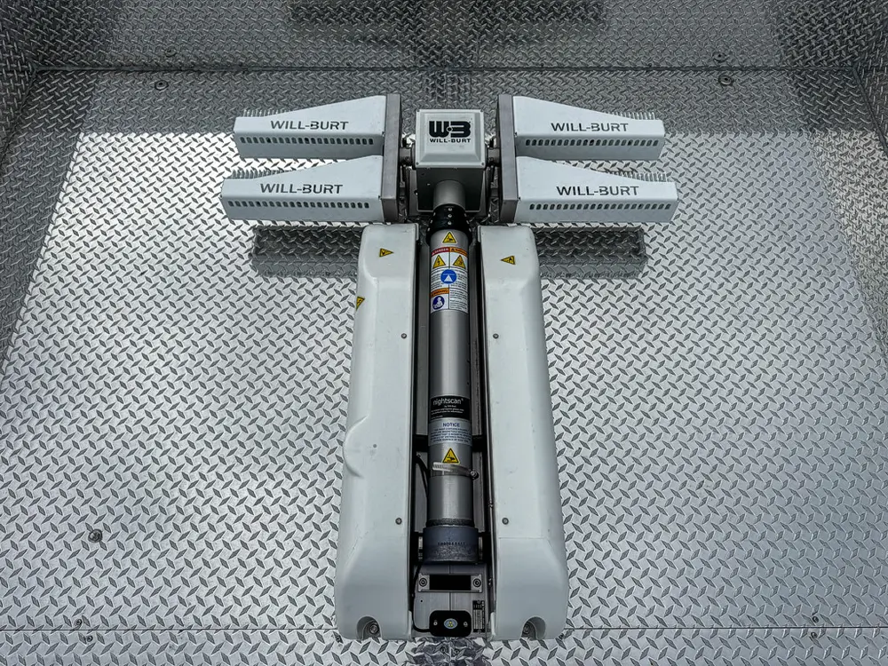 Exterior view of small fire truck showing cab, body compartments, and wheel/tire area.