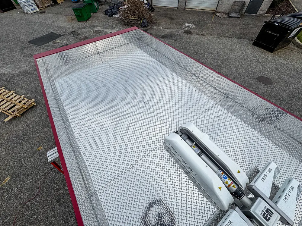 Exterior view of small fire truck showing cab, body compartments, and wheel/tire area.