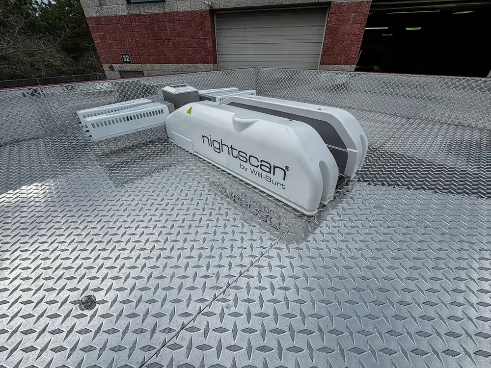 Exterior view of small fire truck showing cab, body compartments, and wheel/tire area.