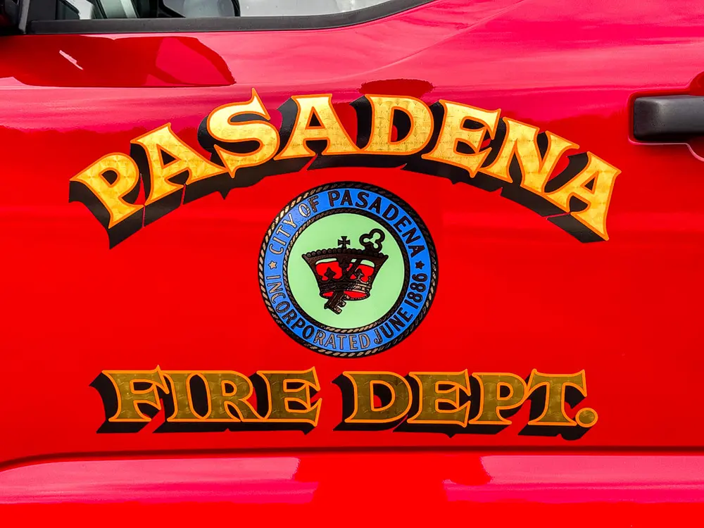 Exterior view of small fire truck showing cab, body compartments, and wheel/tire area.