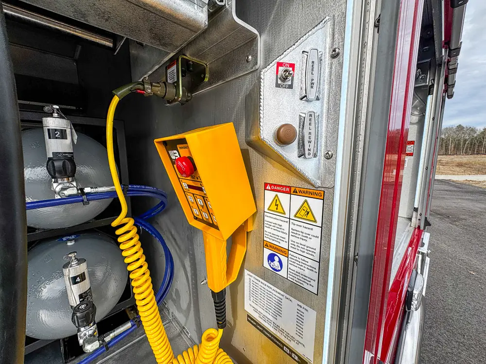 Detail view of yellow control pendant and safety labels inside compartment.