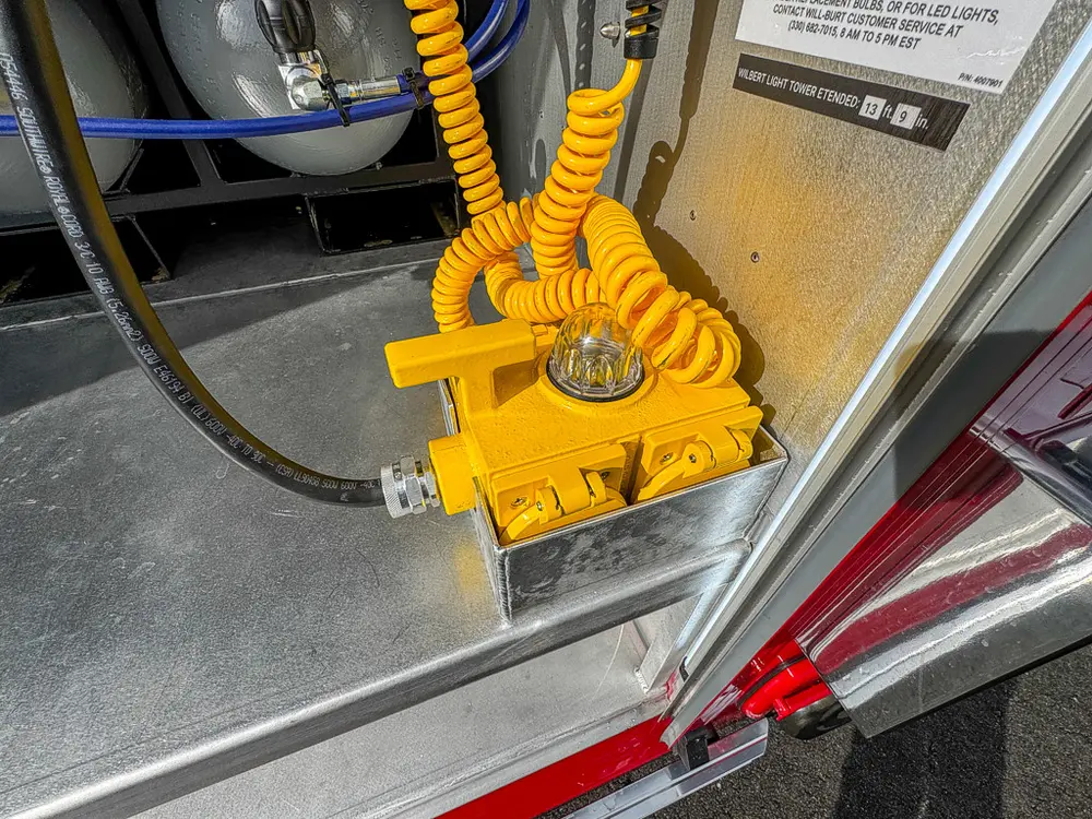 Close detail of yellow foot control and coiled cable at compartment edge.