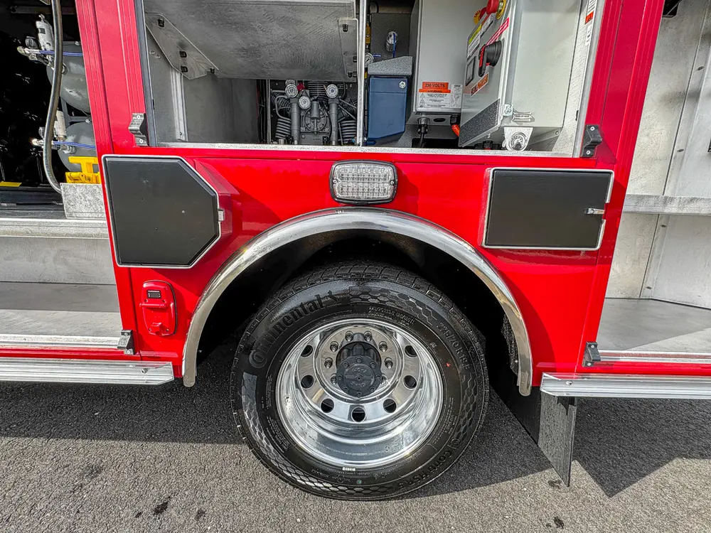 Close view of rear wheel, fender, and lower compartment trim.