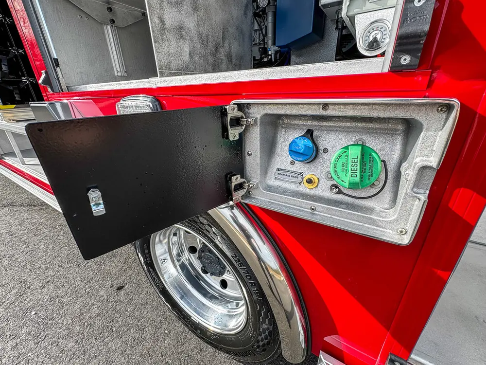 Open fuel and DEF fill panel near rear wheel.