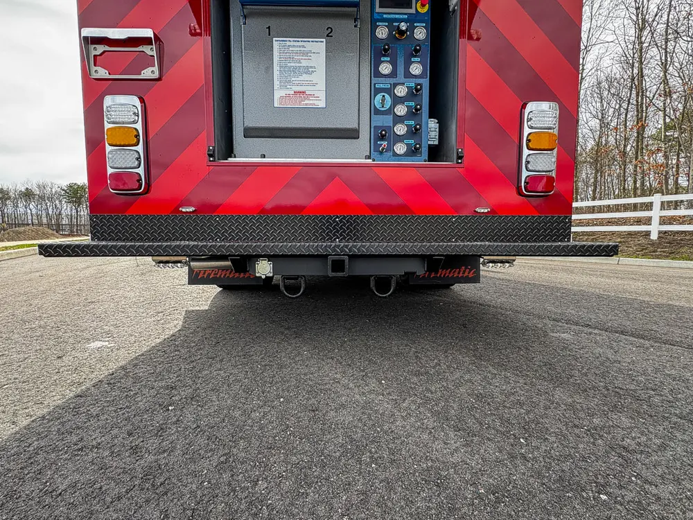 Exterior view of small fire truck showing cab, body compartments, and wheel/tire area.