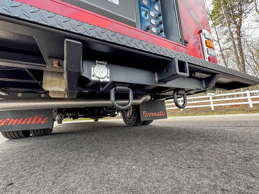 Exterior view of small fire truck showing cab, body compartments, and wheel/tire area.