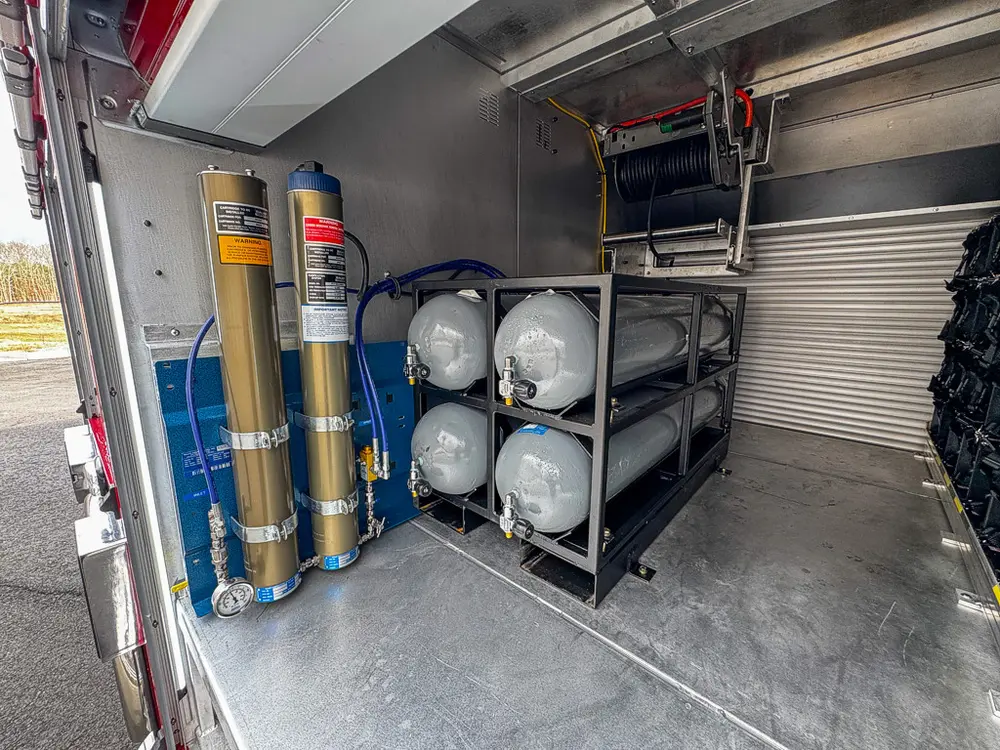 Exterior view of small fire truck showing cab, body compartments, and wheel/tire area.