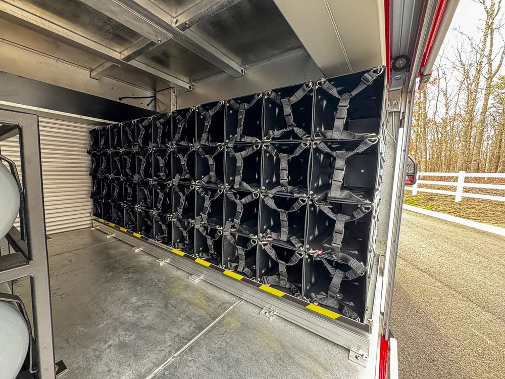 Exterior view of small fire truck showing cab, body compartments, and wheel/tire area.