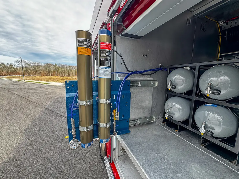 Exterior view of small fire truck showing cab, body compartments, and wheel/tire area.