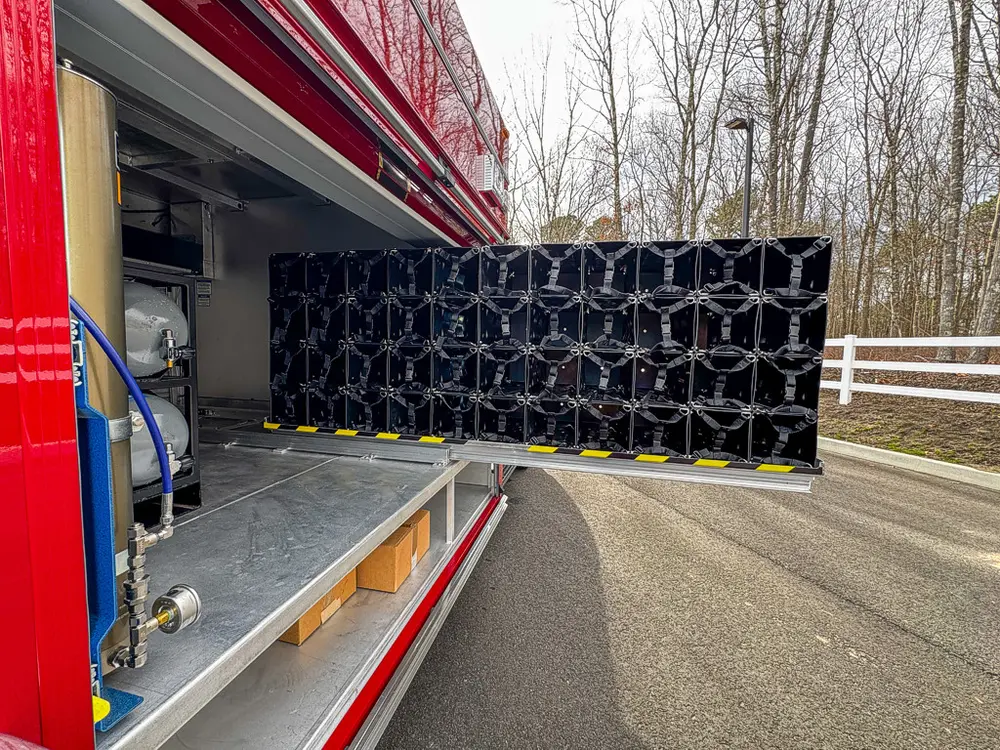 Exterior view of small fire truck showing cab, body compartments, and wheel/tire area.