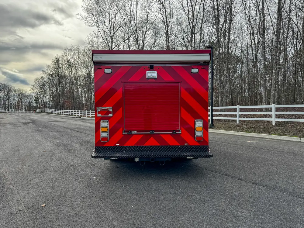 Direct rear view with red chevron striping and rear roll-up door.