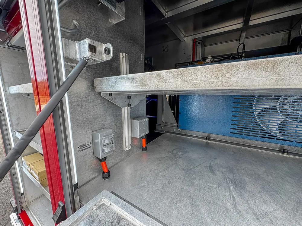 Exterior view of small fire truck showing cab, body compartments, and wheel/tire area.