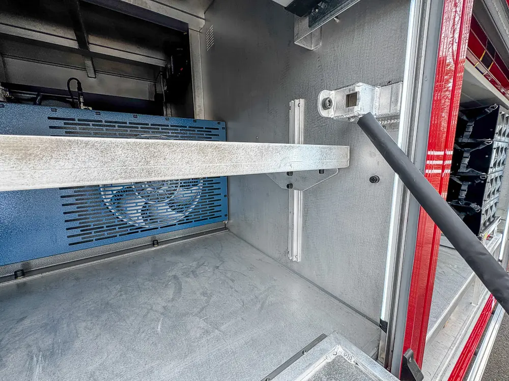 Exterior view of small fire truck showing cab, body compartments, and wheel/tire area.