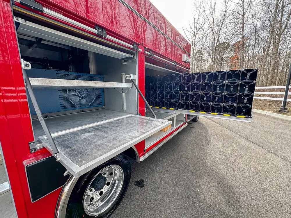 Exterior view of small fire truck showing cab, body compartments, and wheel/tire area.