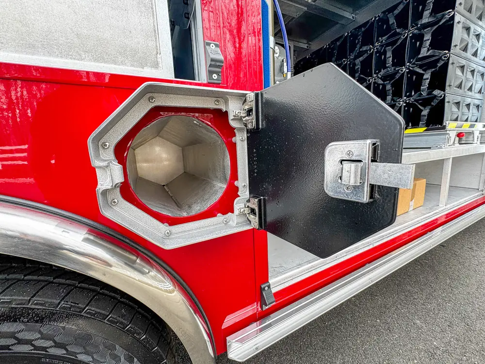 Exterior view of small fire truck showing cab, body compartments, and wheel/tire area.