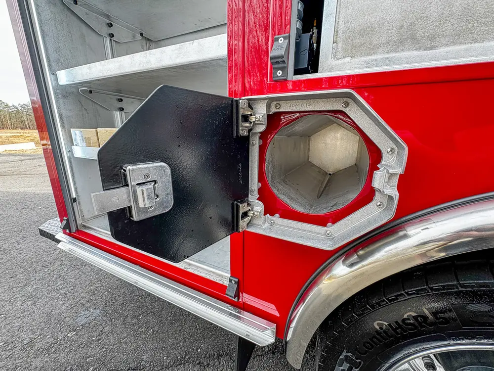 Exterior view of small fire truck showing cab, body compartments, and wheel/tire area.