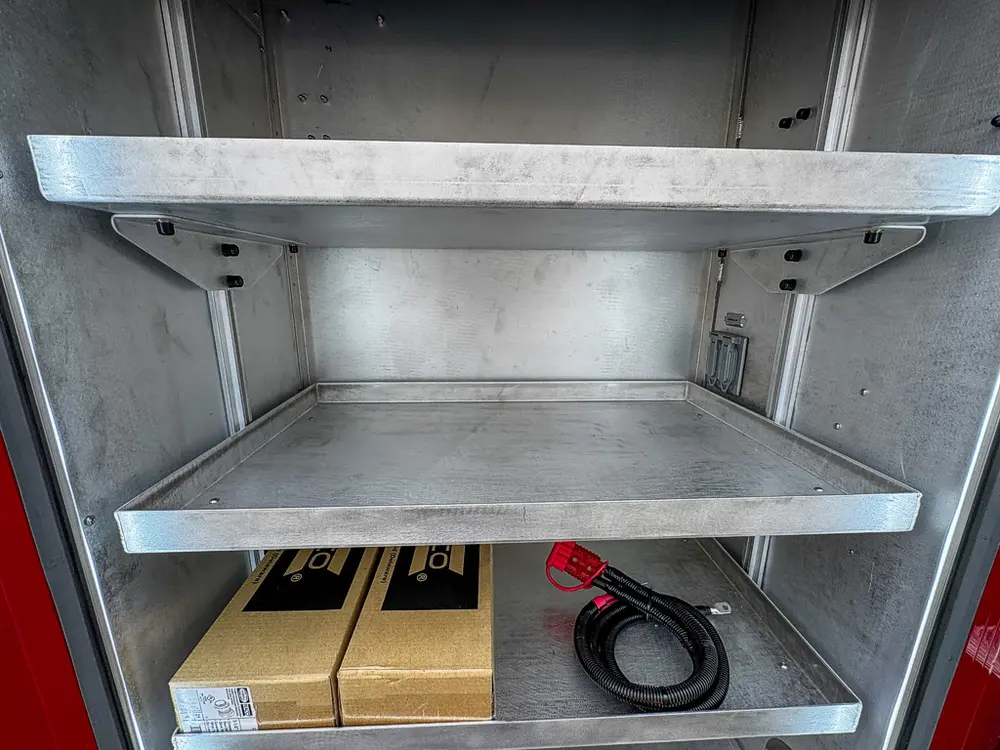 Exterior view of small fire truck showing cab, body compartments, and wheel/tire area.