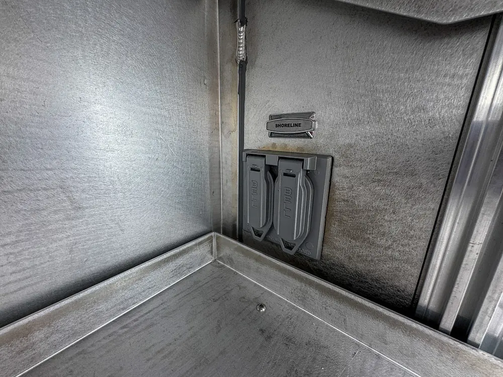 Exterior view of small fire truck showing cab, body compartments, and wheel/tire area.