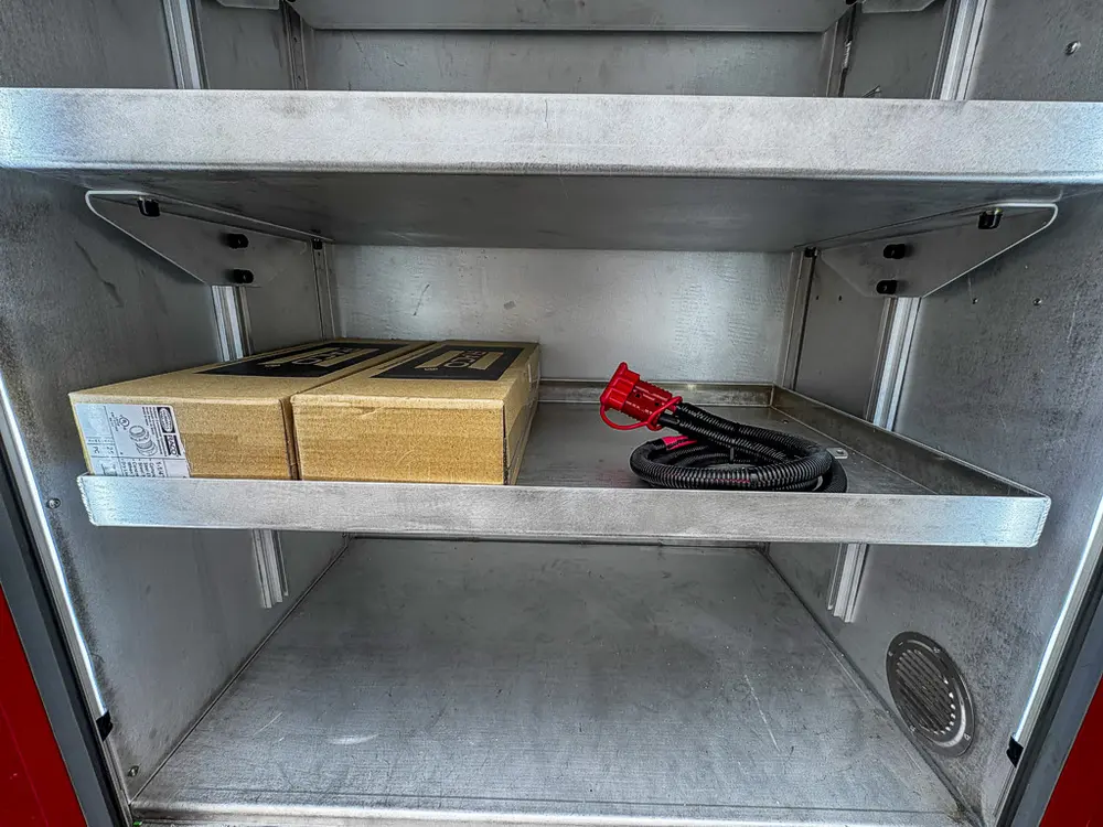 Exterior view of small fire truck showing cab, body compartments, and wheel/tire area.