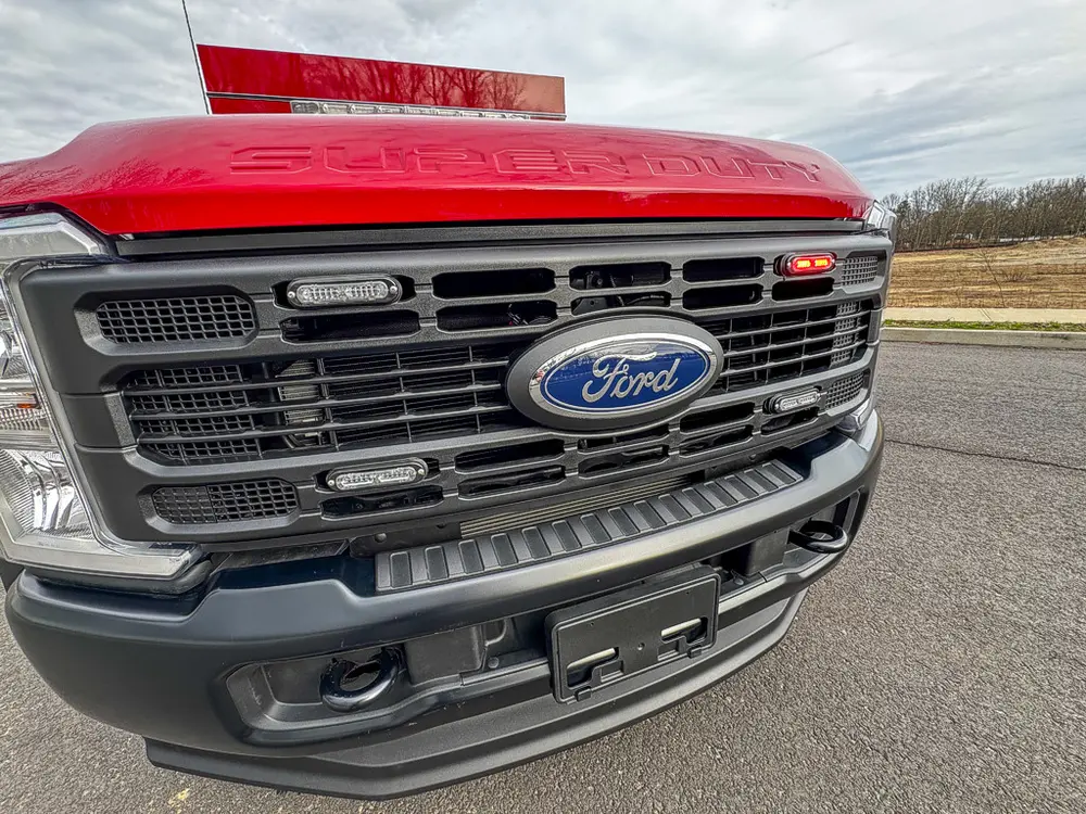 Exterior view of small fire truck showing cab, body compartments, and wheel/tire area.