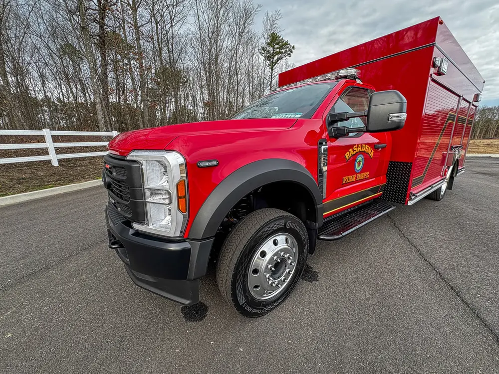 Exterior view of small fire truck showing cab, body compartments, and wheel/tire area.
