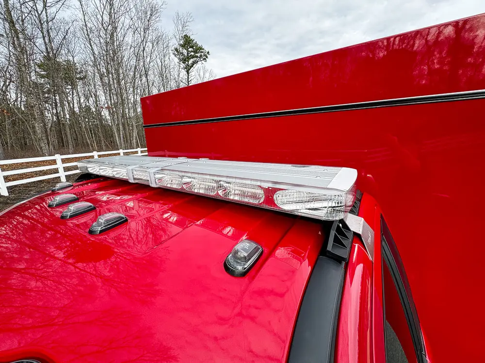 Exterior view of small fire truck showing cab, body compartments, and wheel/tire area.