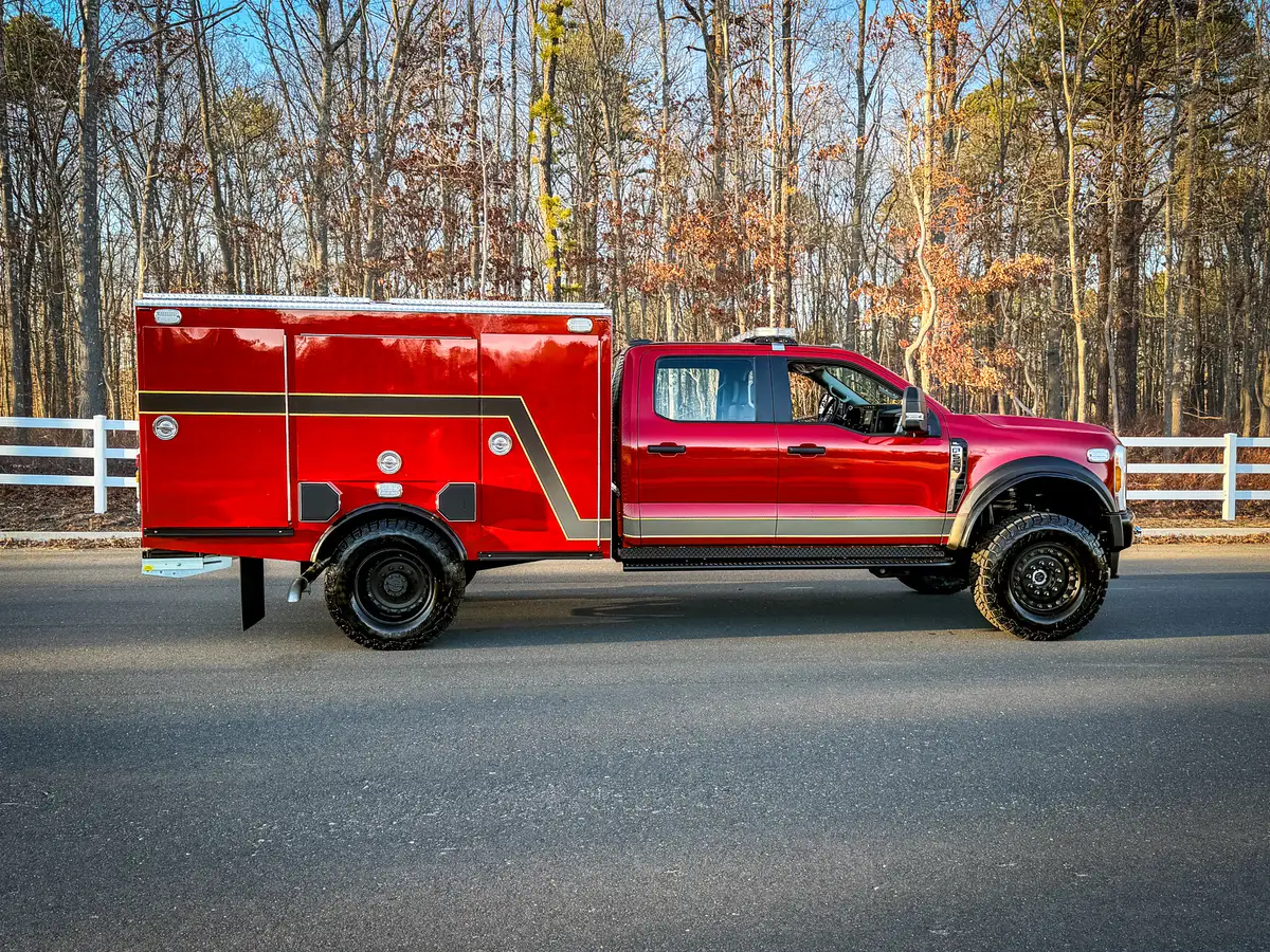Full left-side profile of red brush truck parked on roadway.