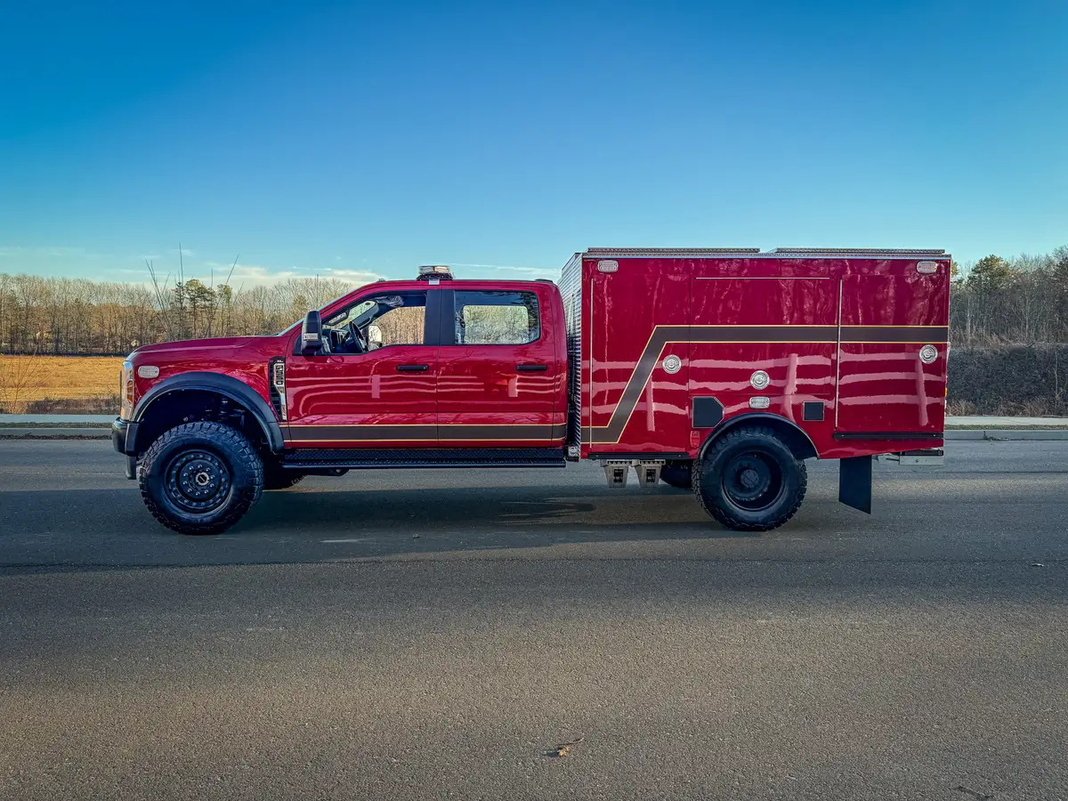 Full right-side profile of red brush truck parked on roadway.