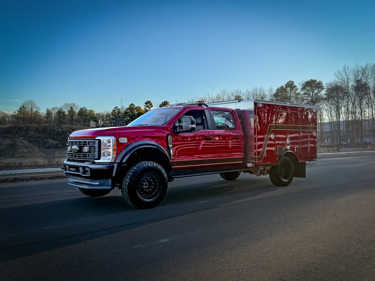 Front three-quarter view from driver side of red brush truck.