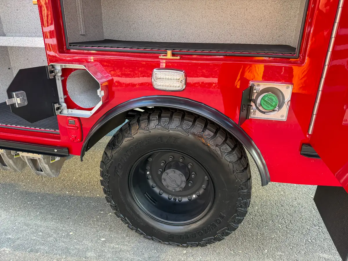 Rear wheel area with utility access doors open, exposing fill ports.