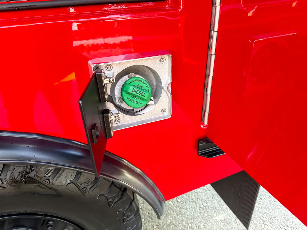 Close-up of diesel fill port behind small hinged access door.