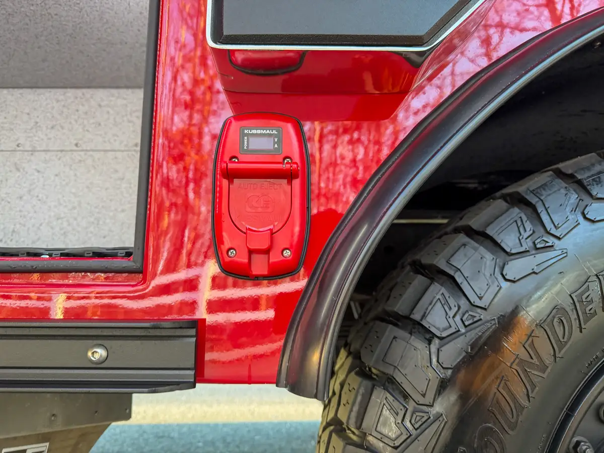 Close-up of red auto-eject power inlet near rear wheel arch.