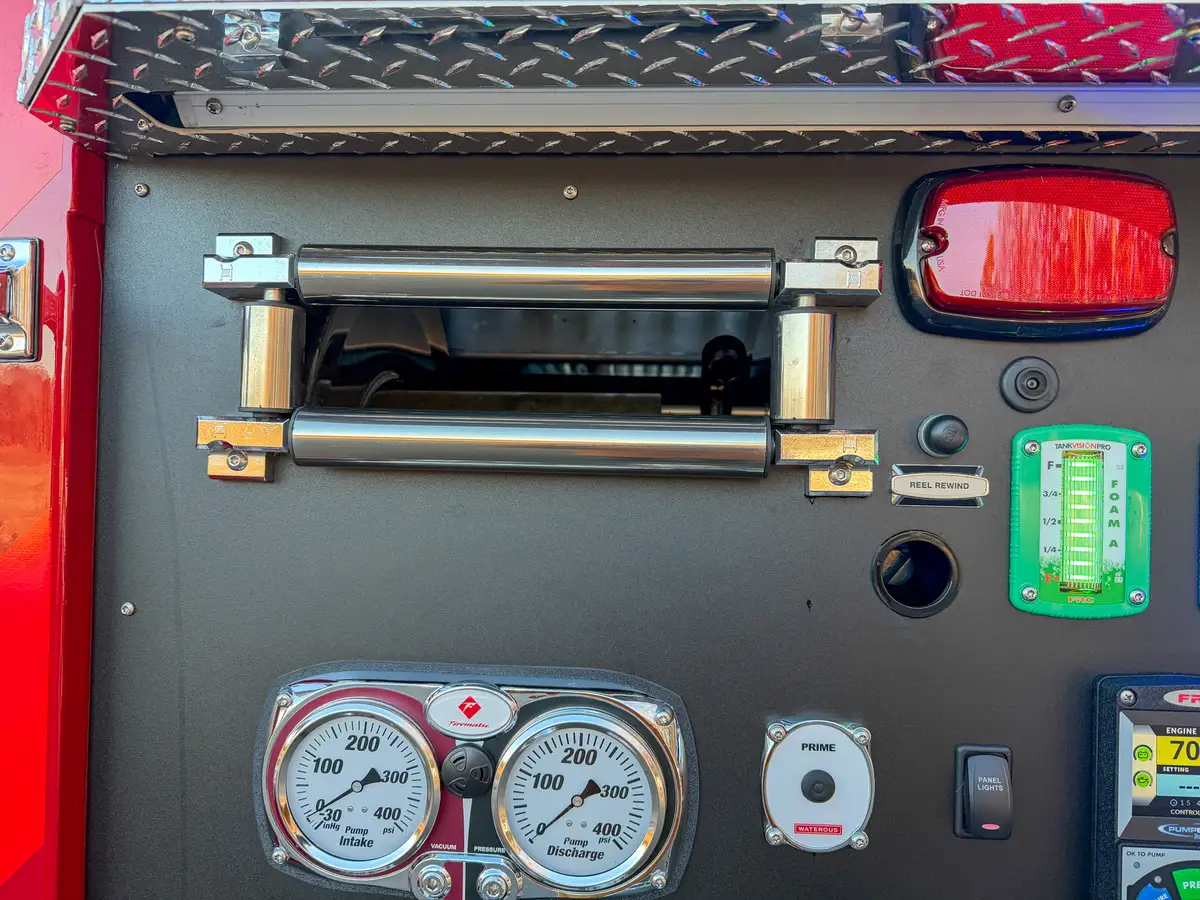 Pump panel hose reel opening and controls near warning light.