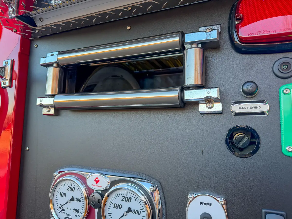 Close-up of hose reel opening and rewind switch above panel gauges.