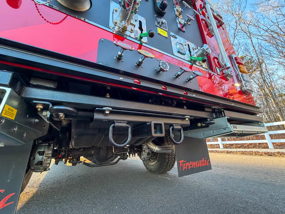 Low angle under rear bumper showing hitch receiver and tow points.