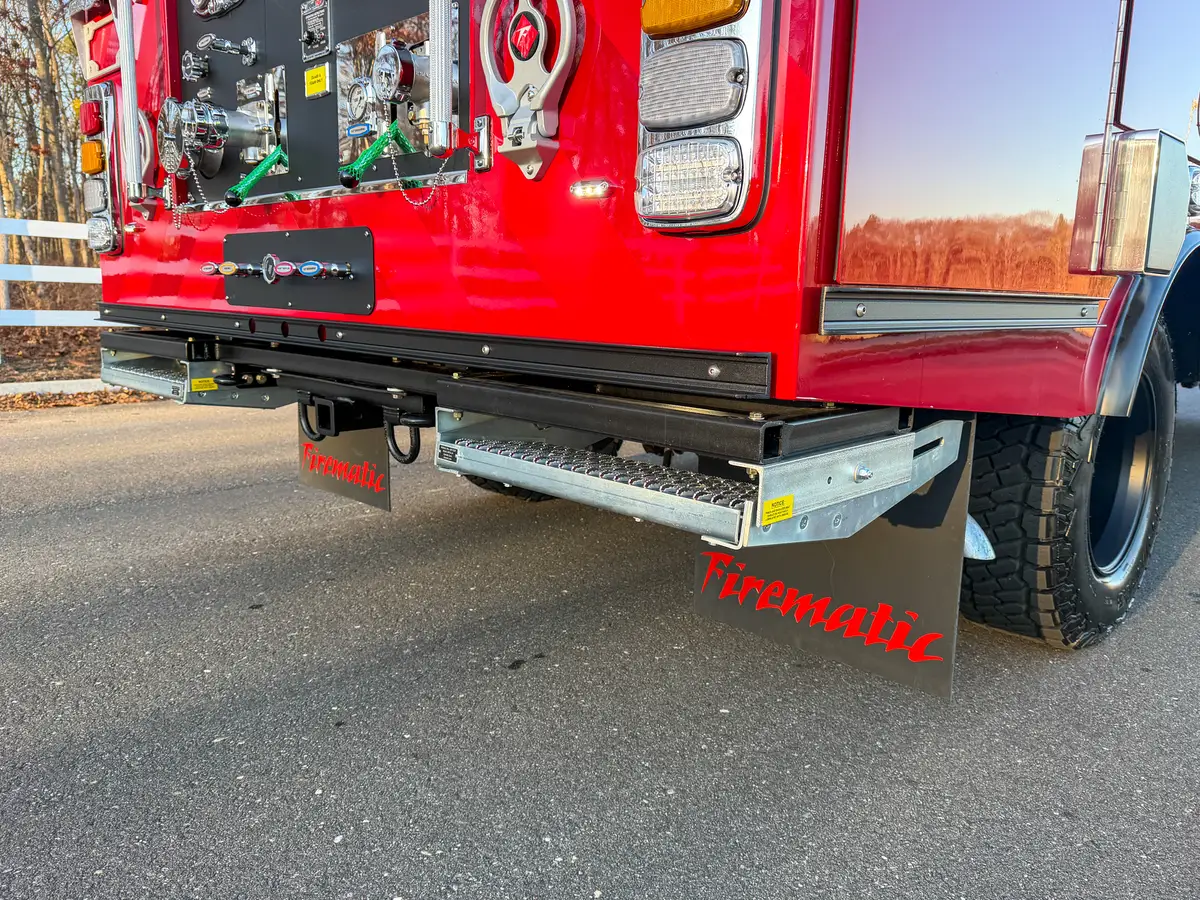 Rear corner view with one slide-out step deployed below pump panel.