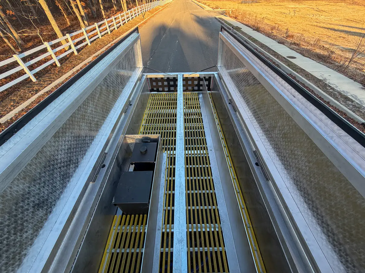 Top-down view into open rear deck trough with grated floor and center divider.