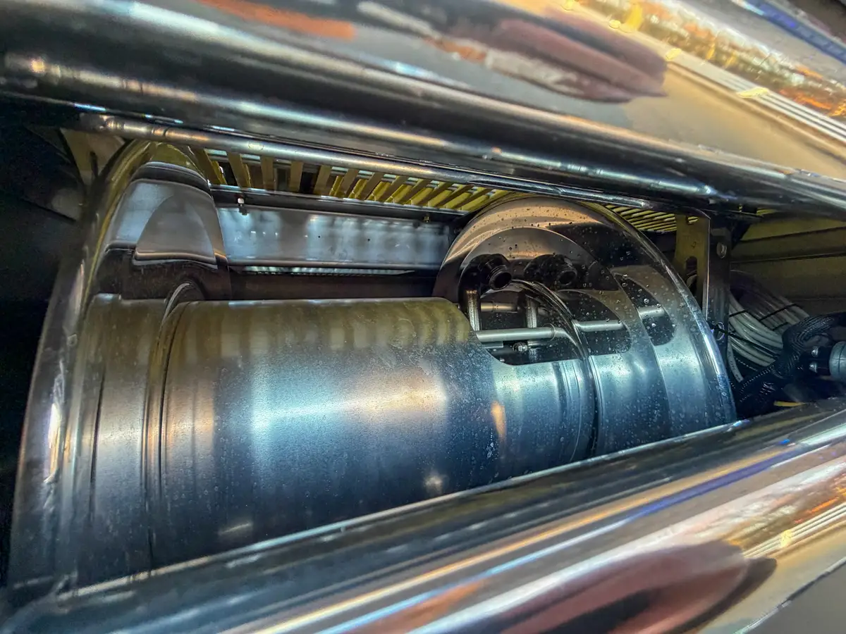 Close-up inside upper rear compartment showing hose reel drum and hardware.