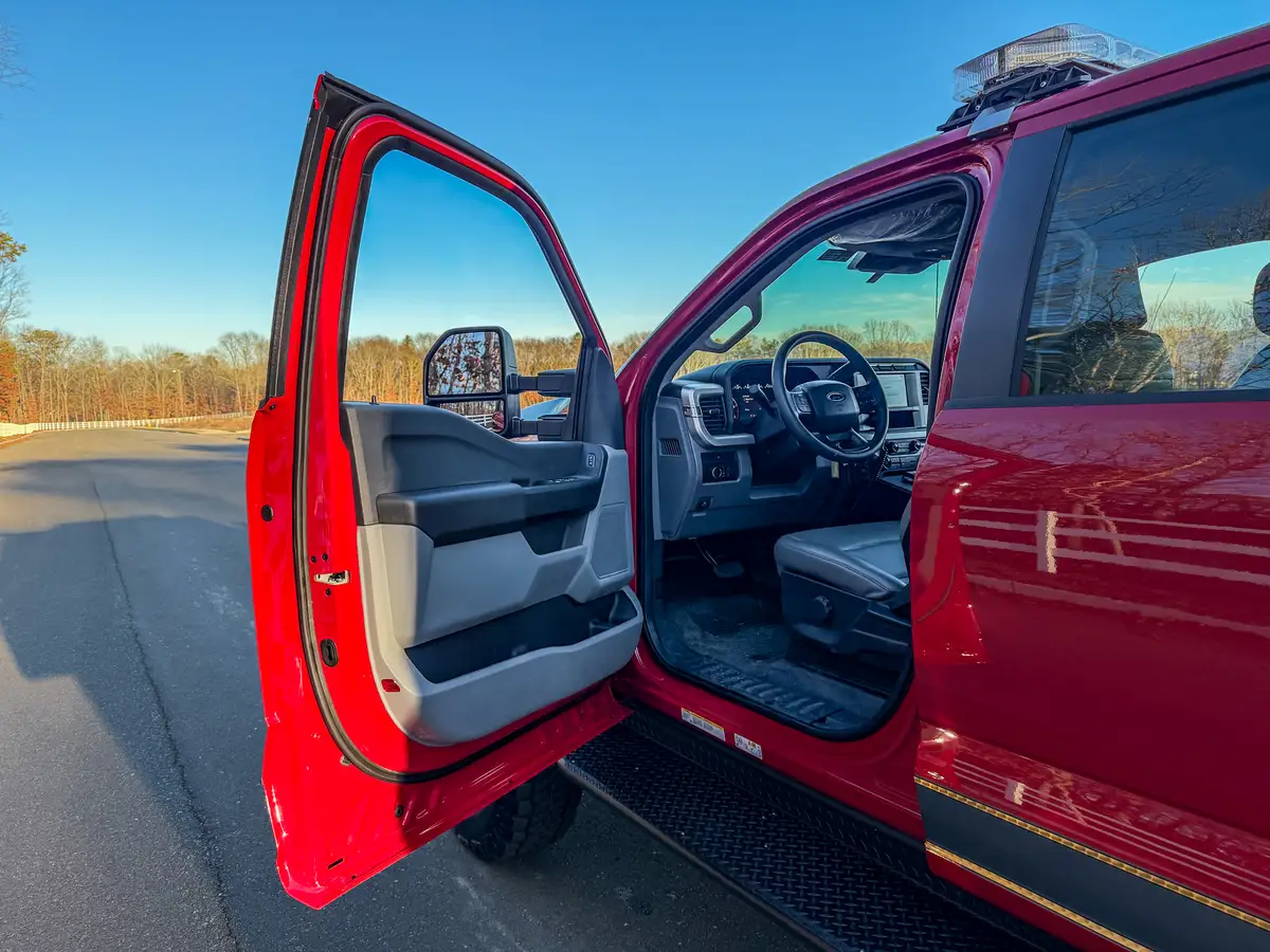 Driver door open view showing steering wheel, front seat, and cab entry area.