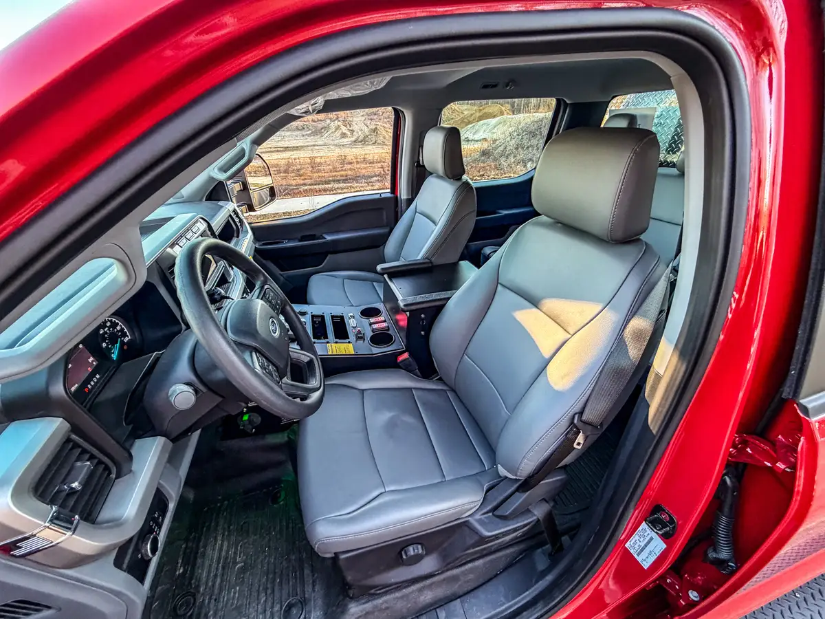 Driver-side interior view with front seat, steering wheel, and console controls.