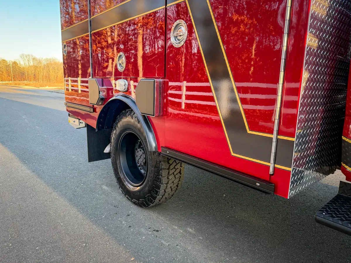 Rear side body and wheel close-up with compartment doors and striping visible.