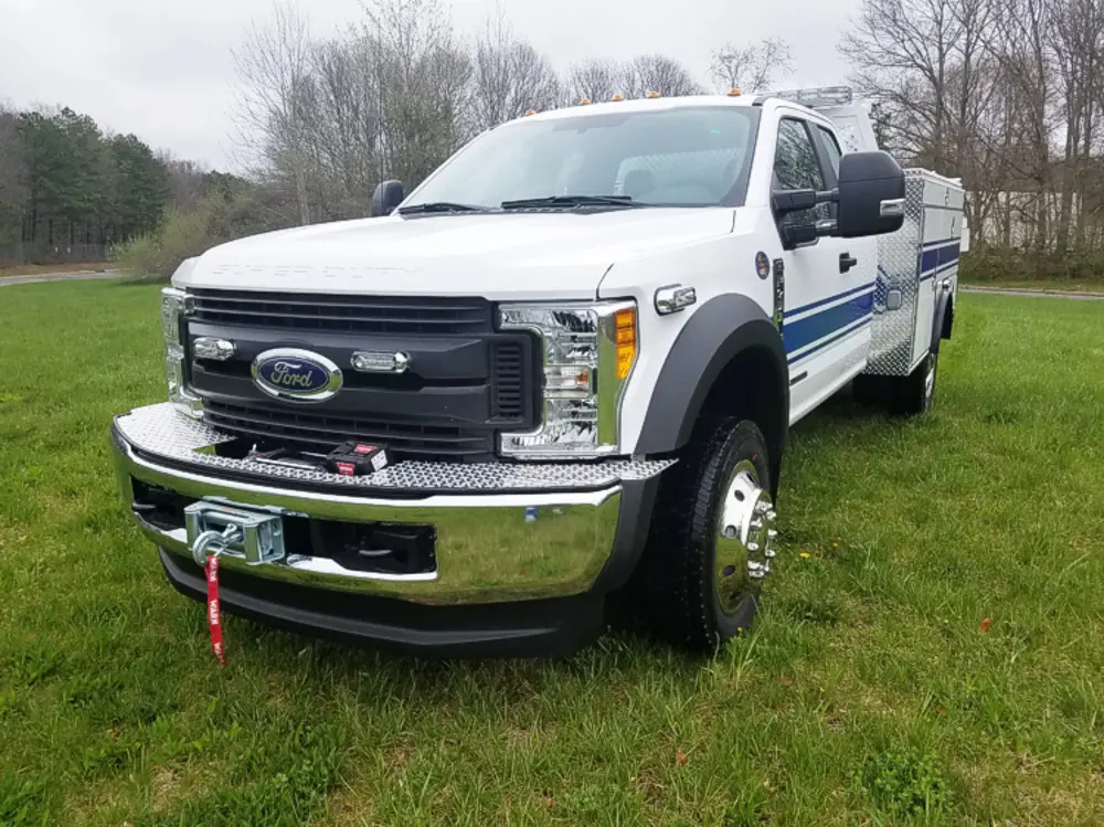 Exterior view of small fire truck showing cab, body compartments, and wheel/tire area.