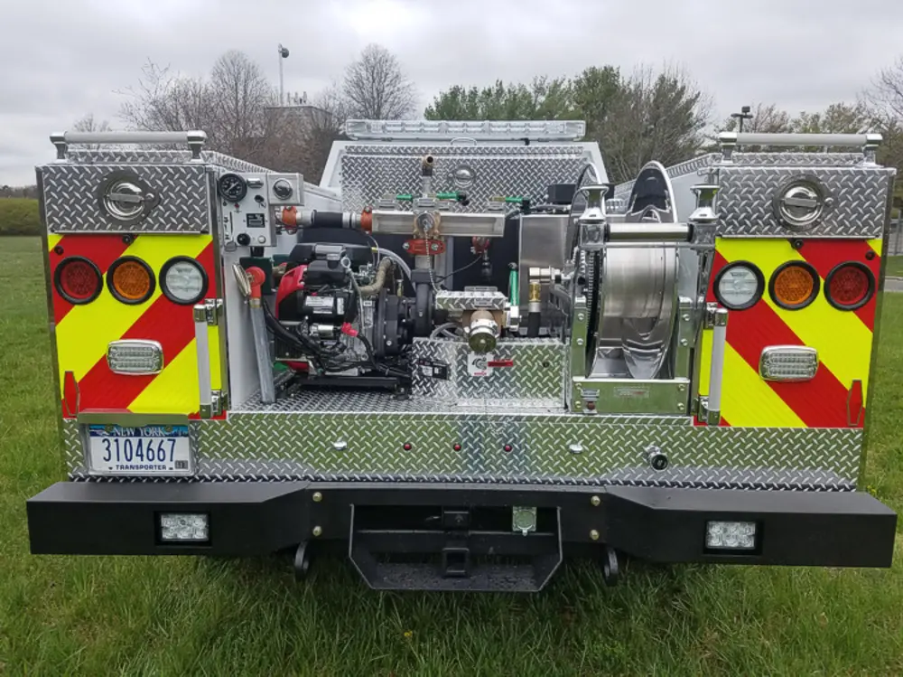 Exterior view of small fire truck showing cab, body compartments, and wheel/tire area.