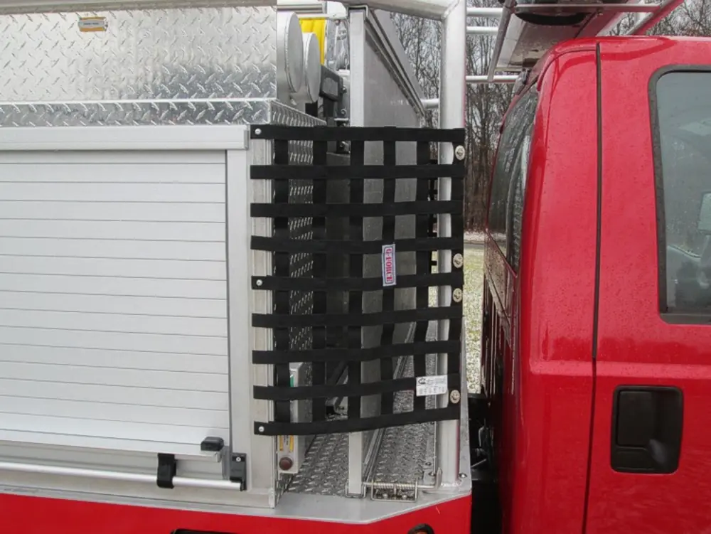 Exterior view of small fire truck showing cab, body compartments, and wheel/tire area.